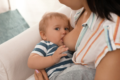 Woman breastfeeding her little baby at home, closeup