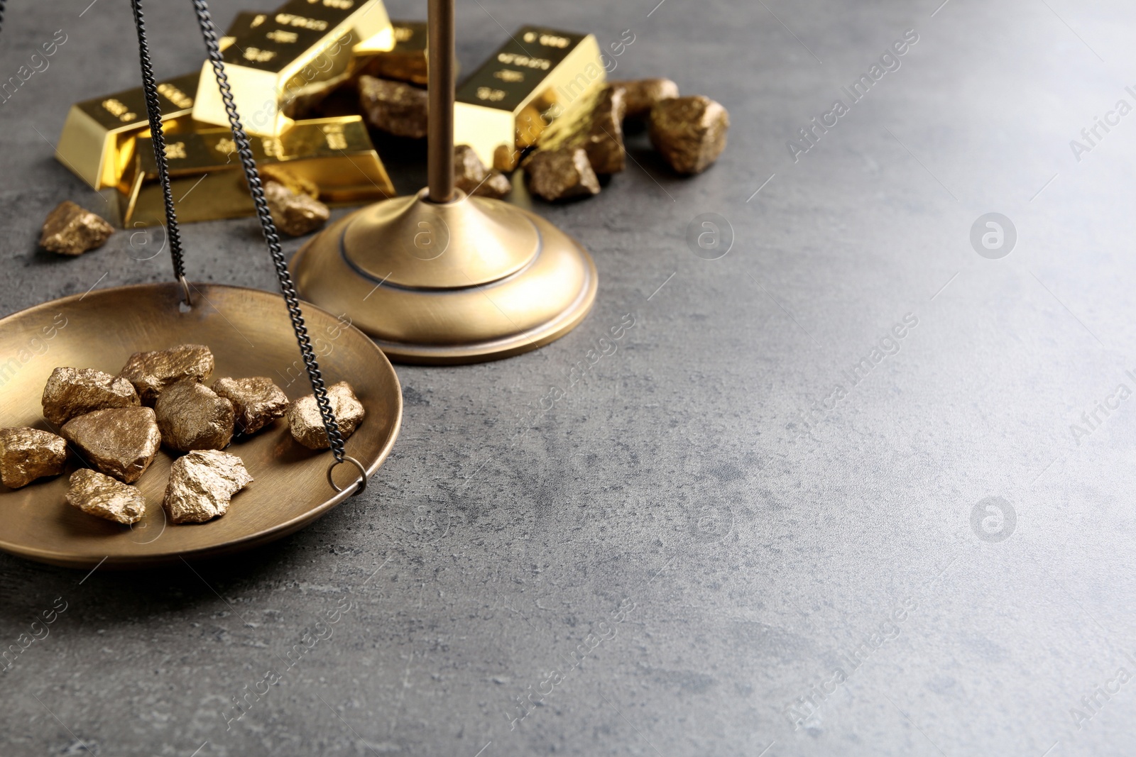 Photo of Scale pan with gold lumps on grey table. Space for text