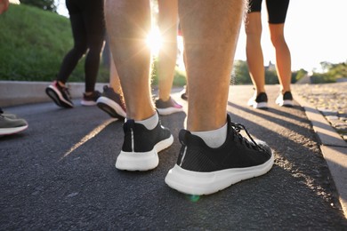 Photo of Group of people resting after run outdoors on sunny day, closeup view