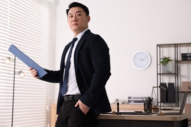 Portrait of confident notary with clipboard in office