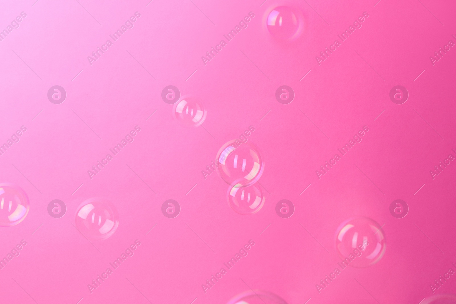 Photo of Beautiful transparent soap bubbles on pink background