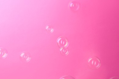 Photo of Beautiful transparent soap bubbles on pink background