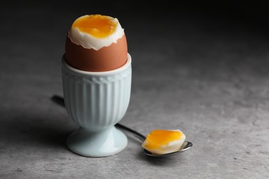 Photo of Cup with fresh soft boiled egg on grey table, closeup. Space for text