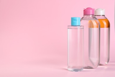 Photo of Bottles of micellar water on pink background. Space for text