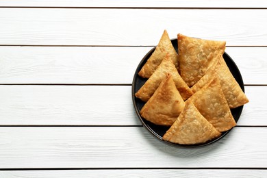 Photo of Fresh delicious crispy samosas on white wooden table, top view. Space for text