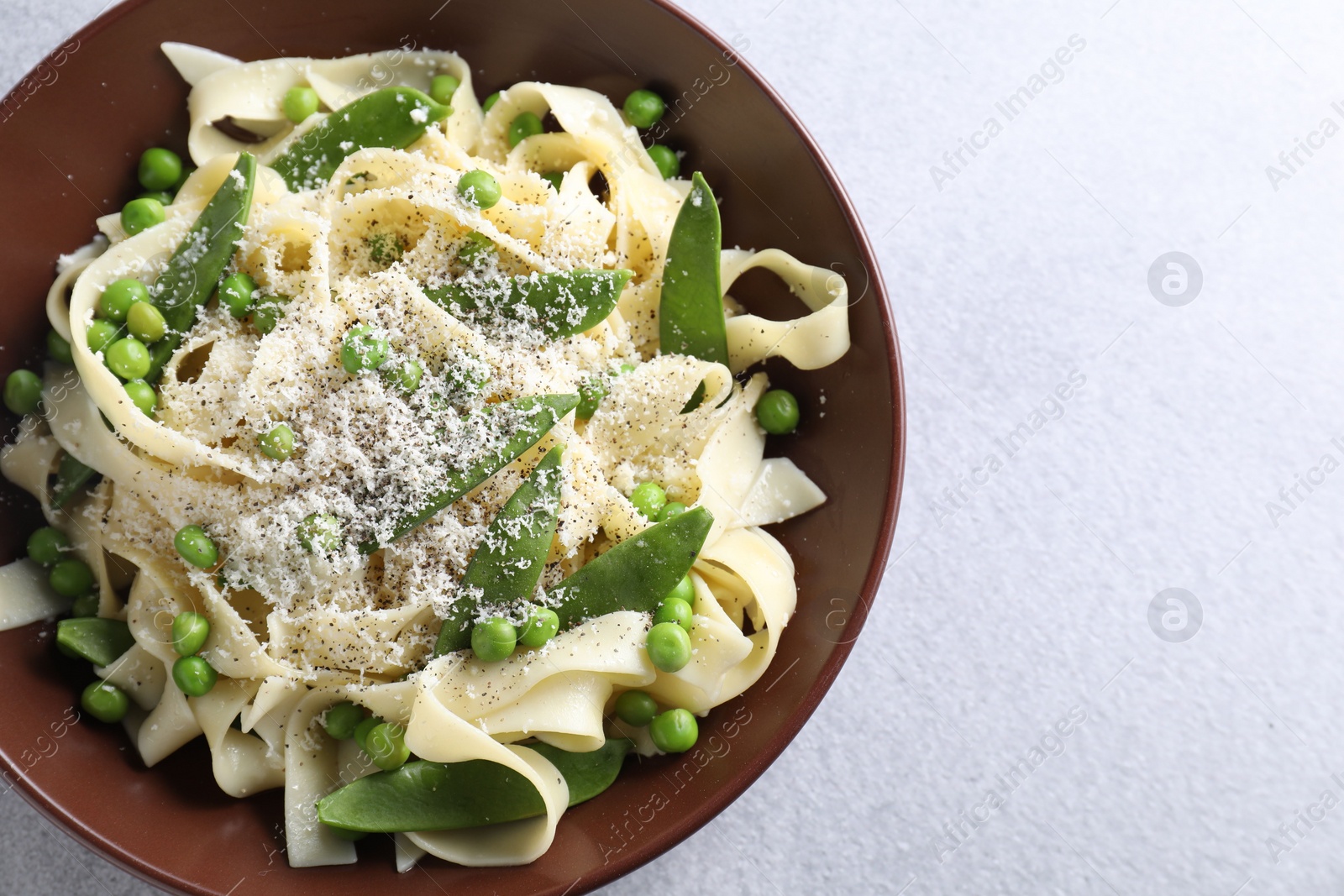 Photo of Delicious pasta with green peas and cheese on grey table, top view. Space for text