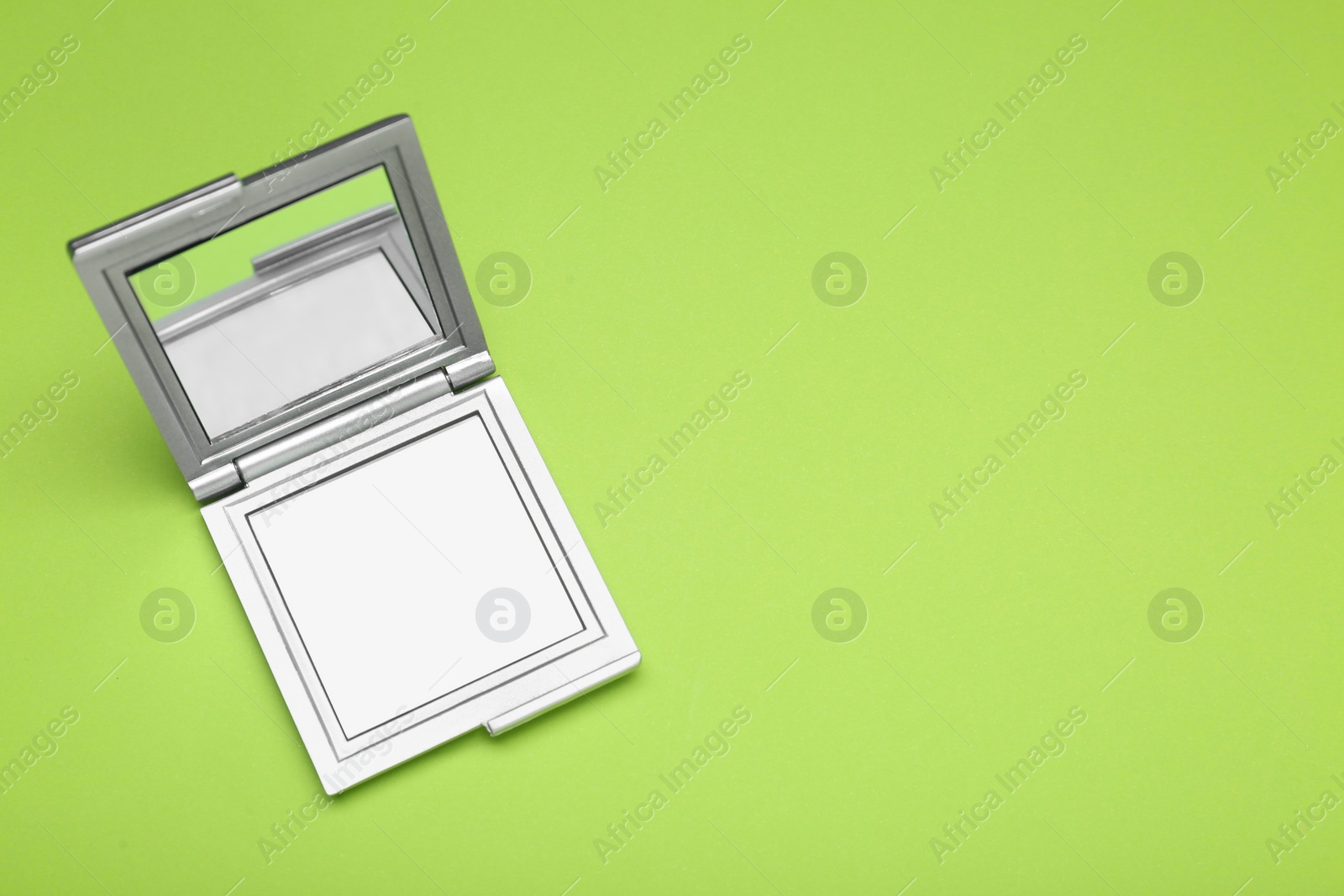 Photo of Stylish cosmetic pocket mirror on light green background, top view. Space for text