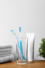 Photo of Plastic toothbrushes, toothpaste and towels on wooden table