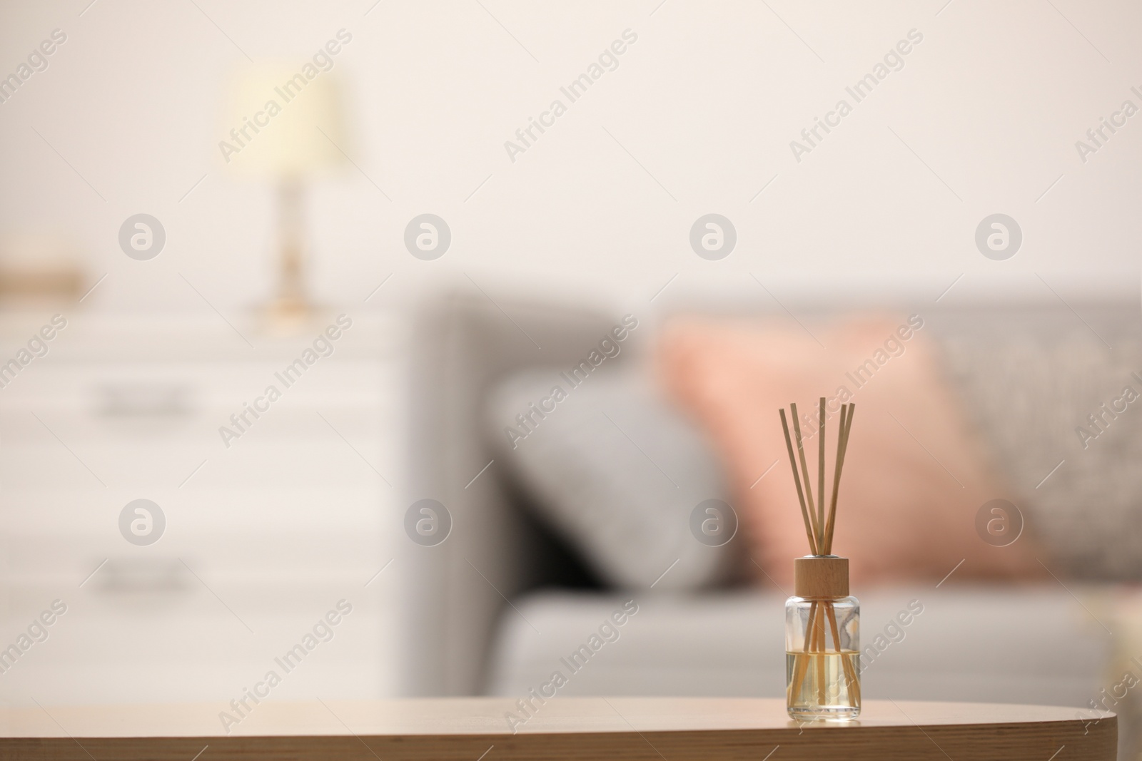 Photo of Reed air freshener with essential oil on table indoors. Space for text