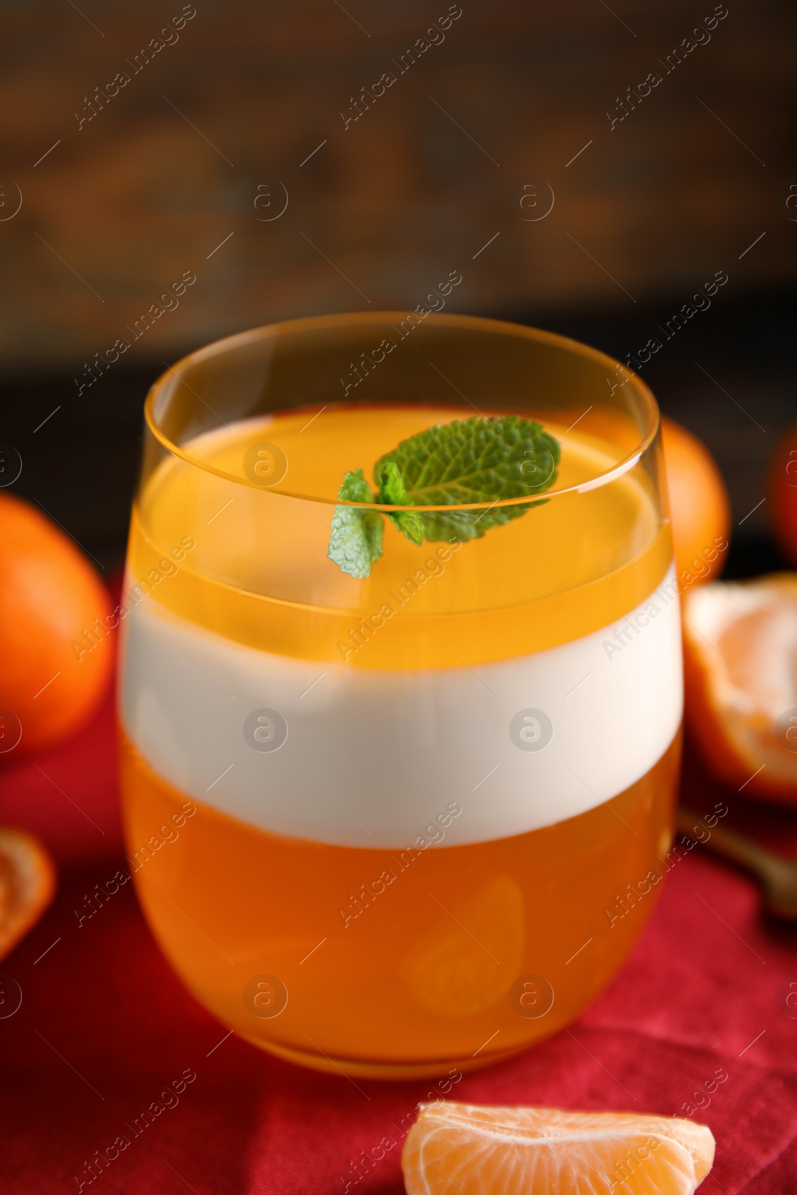 Photo of Delicious tangerine jelly in glass and fresh fruits on table, closeup