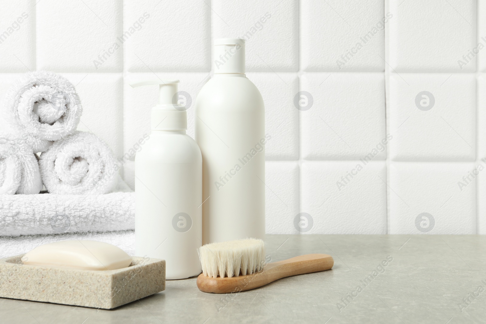 Photo of Different bath accessories and personal care products on gray table near white tiled wall, space for text