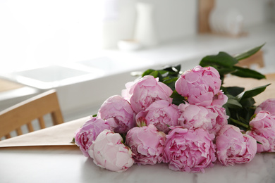 Bouquet of beautiful pink peonies on table in kitchen