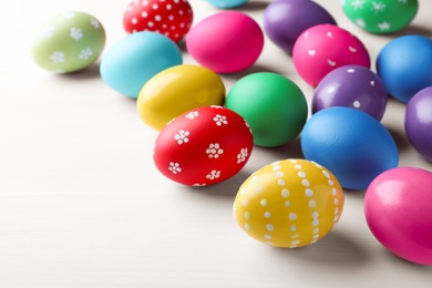 Photo of Bright painted eggs on white wooden table. Happy Easter