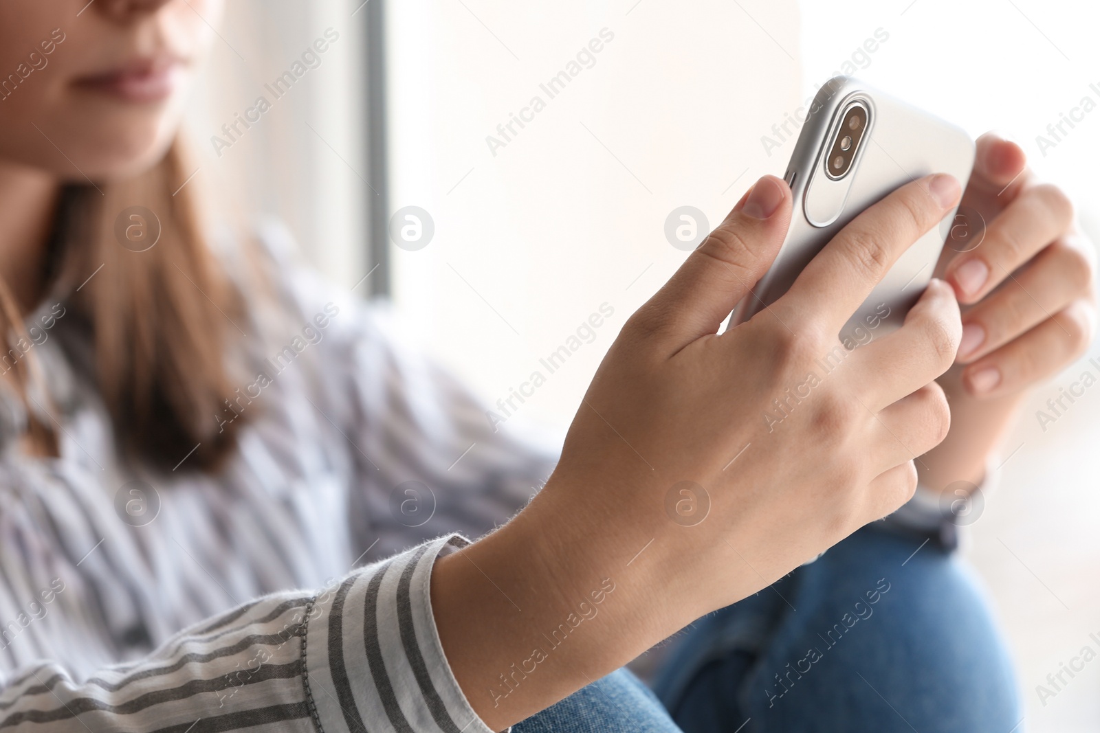 Photo of Young woman holding mobile phone on light background, closeup with space for text. Loneliness concept