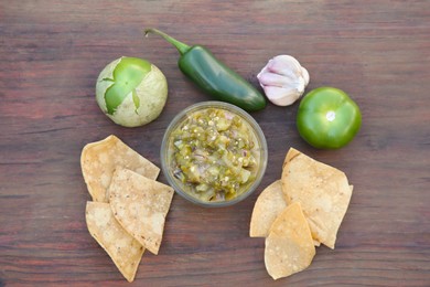 Photo of Tasty salsa sauce, ingredients and tortilla chips on wooden table, flat lay