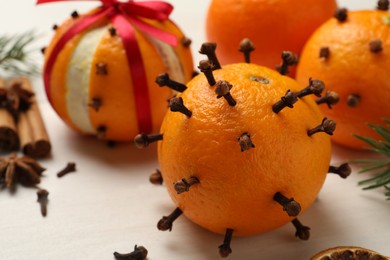 Pomander balls made of tangerines with cloves on white wooden table, closeup