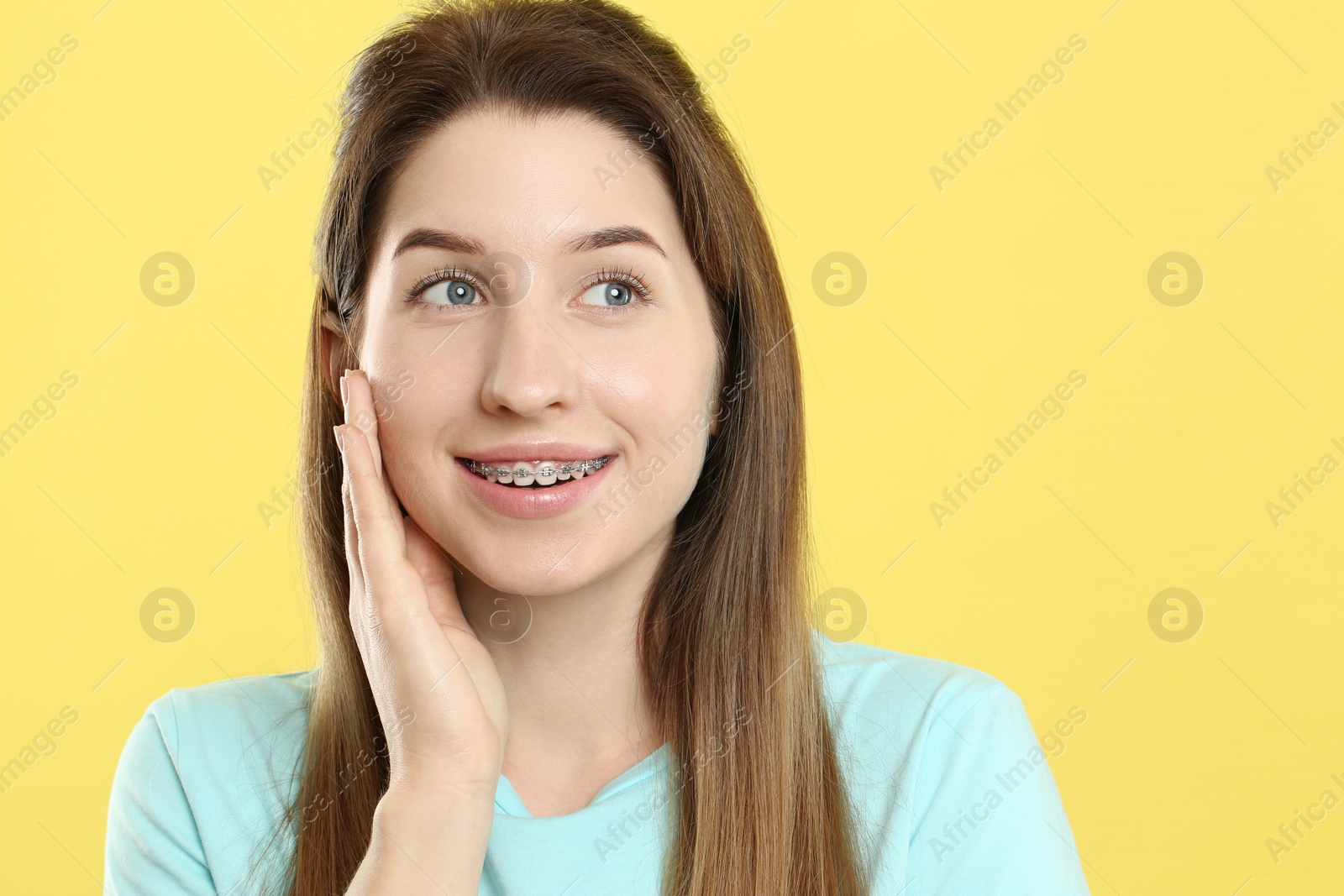 Photo of Portrait of smiling woman with dental braces on yellow background