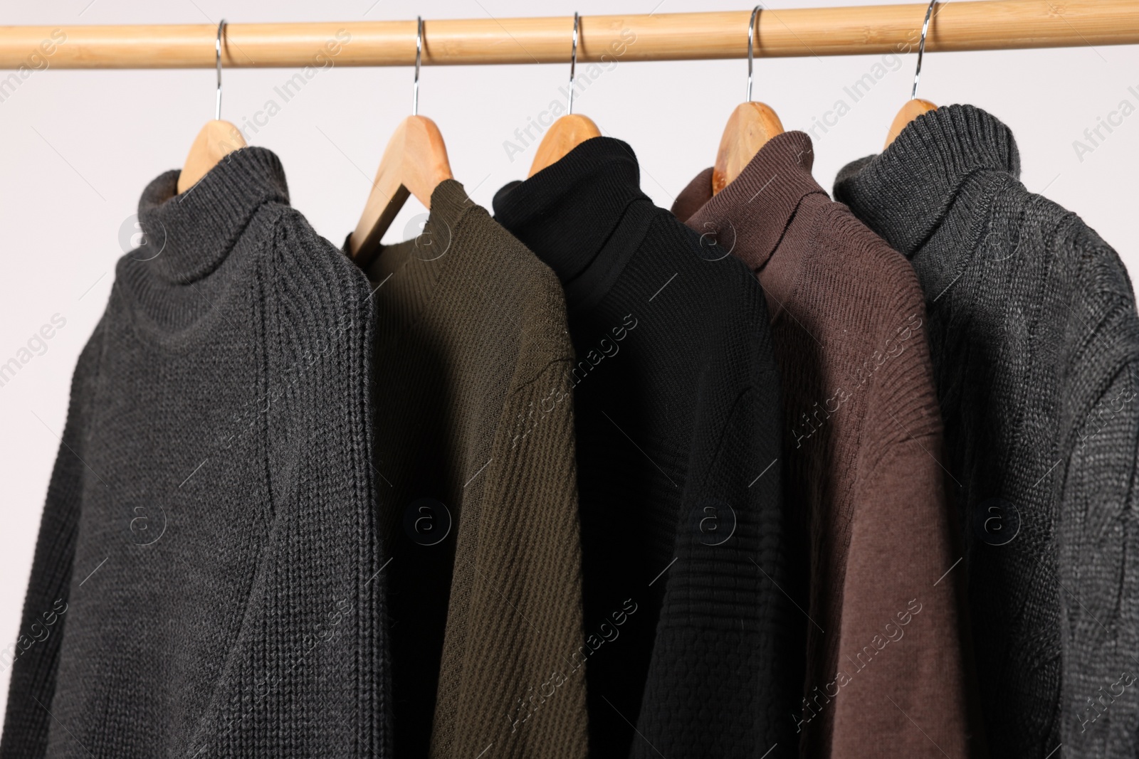 Photo of Rack with different casual sweaters on light background