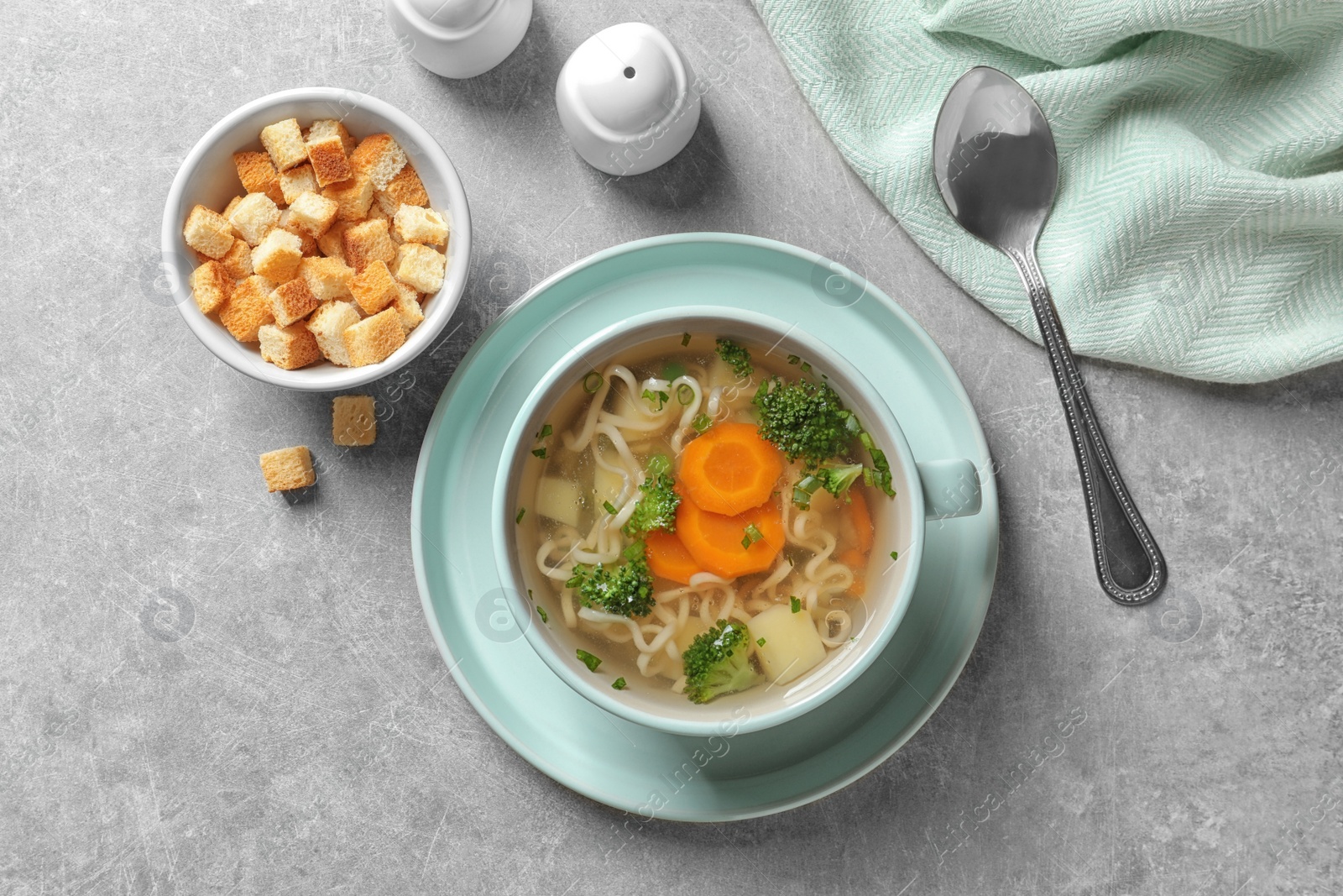 Photo of Dish of fresh homemade vegetable soup served on light grey table, flat lay