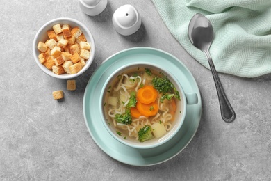 Photo of Dish of fresh homemade vegetable soup served on light grey table, flat lay