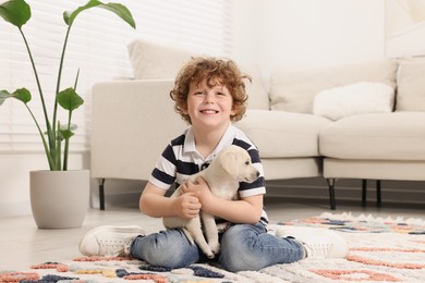 Photo of Little boy with cute puppy on carpet at home