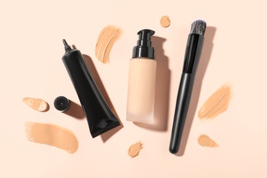 Photo of Liquid foundations, swatches and makeup brush on beige background, flat lay