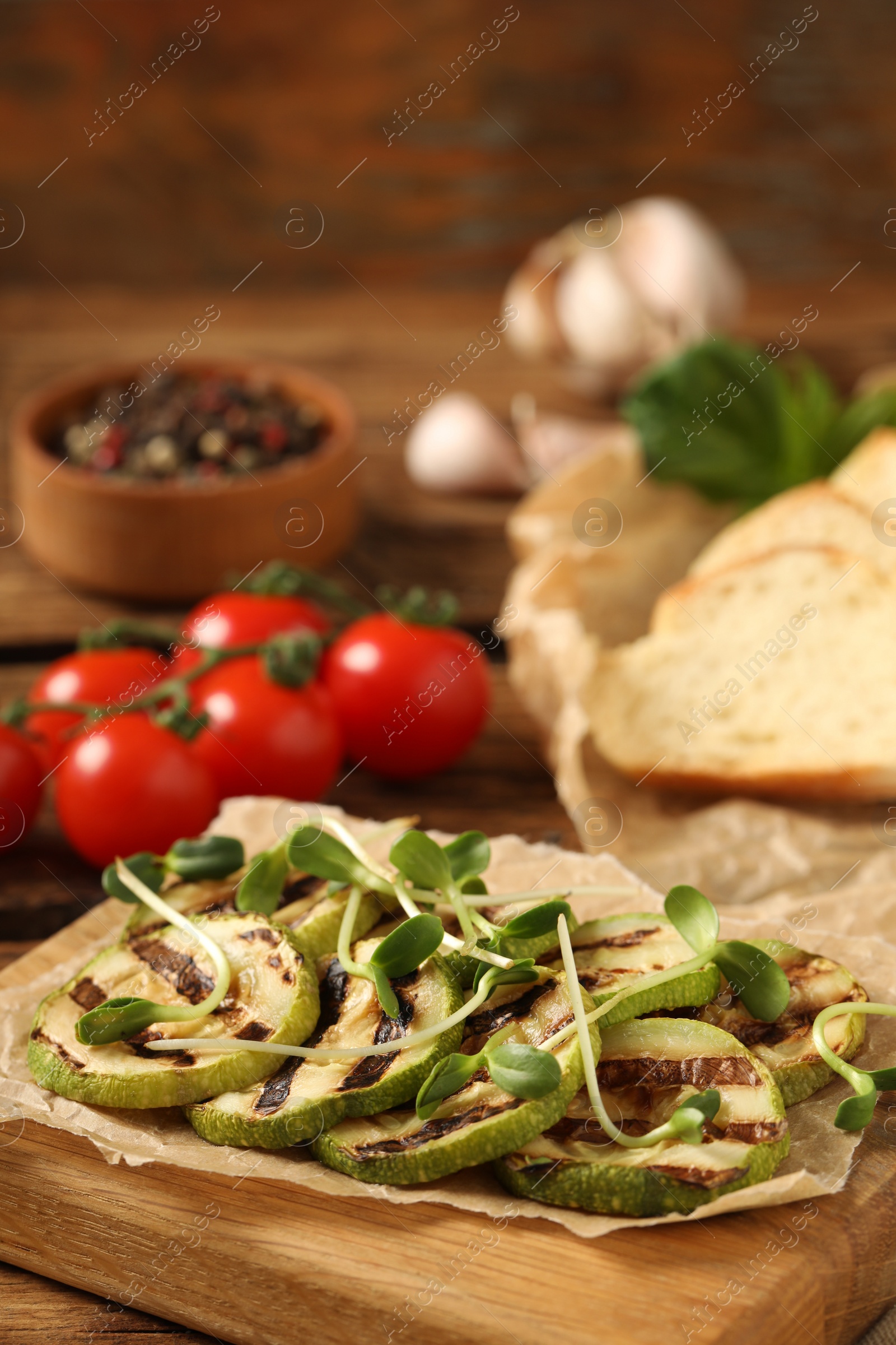 Photo of Delicious grilled zucchini slices with microgreens on wooden board, closeup