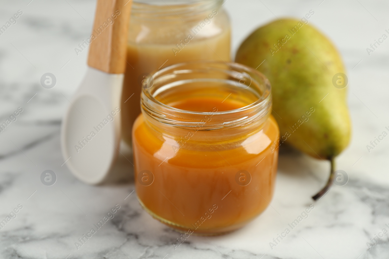 Photo of Tasty baby food in jar on white marble table, closeup