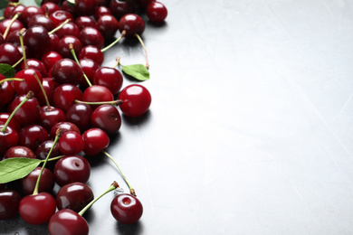 Photo of Sweet juicy cherries with leaves on light table. Space for text