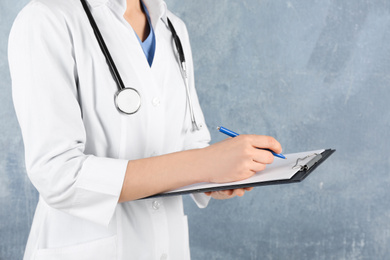 Photo of Doctor with stethoscope and clipboard on blue background, closeup. Medical service