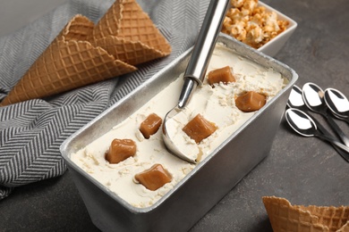 Delicious ice cream in container with caramel on table