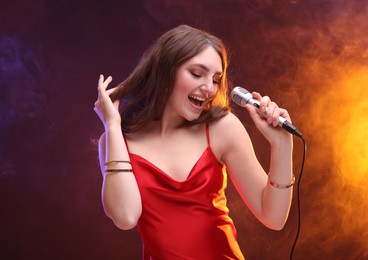 Emotional woman with microphone singing in color lights