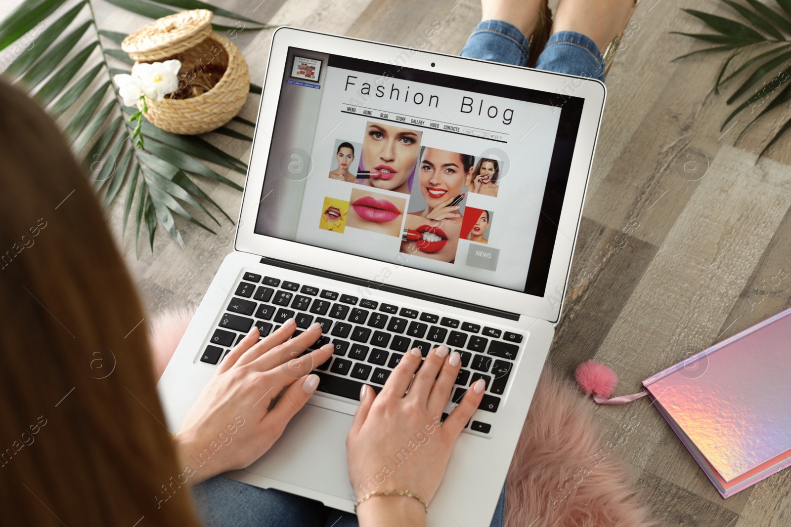 Photo of Woman holding laptop with open fashion blogger site on floor, closeup
