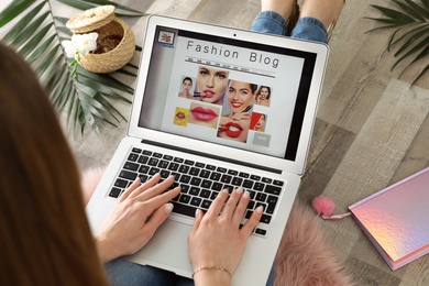 Woman holding laptop with open fashion blogger site on floor, closeup