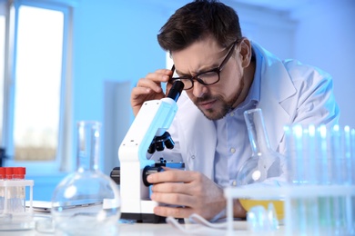 Male scientist using modern microscope in chemistry laboratory