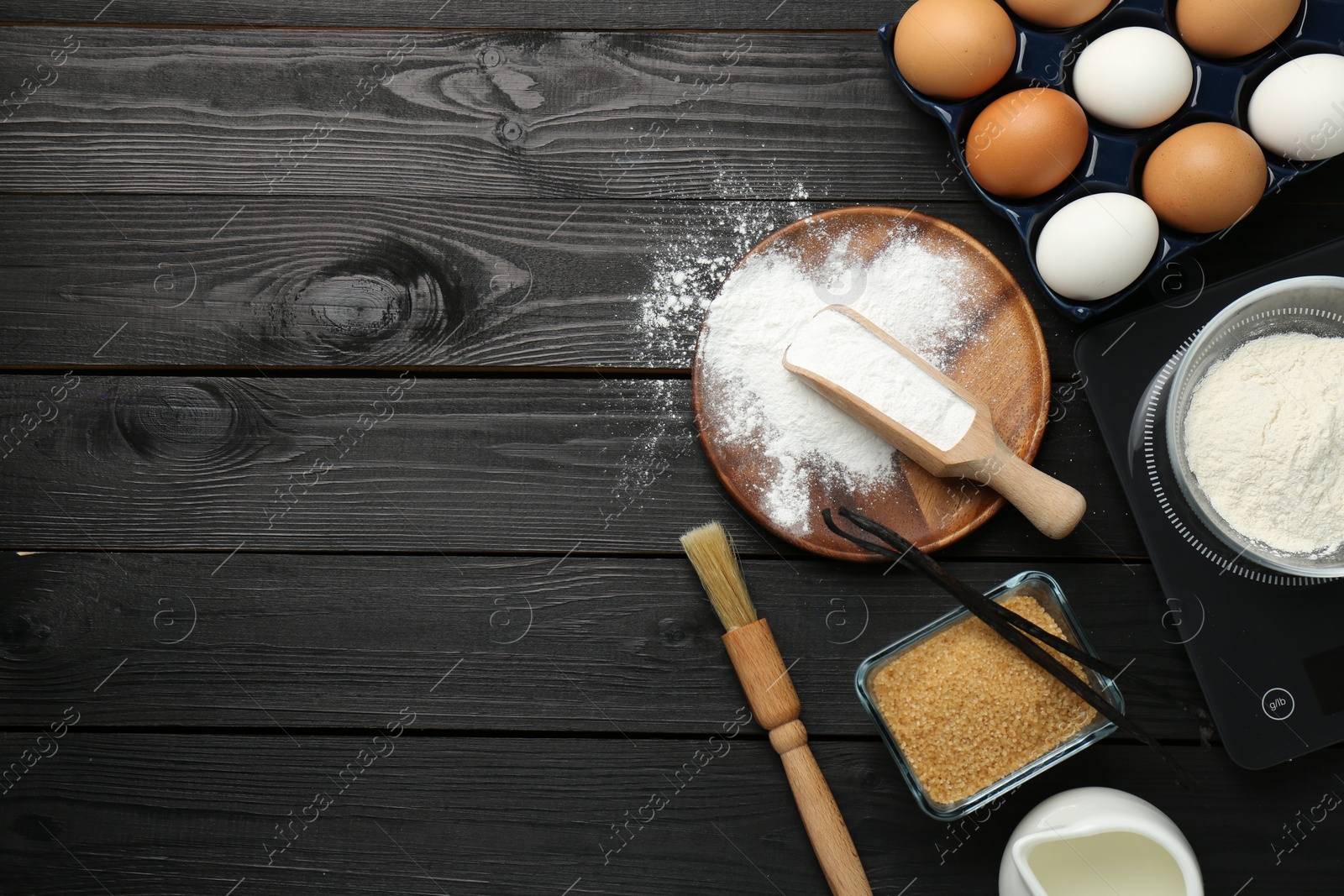 Photo of Flat lay composition with baking powder and products on black wooden table. Space for text