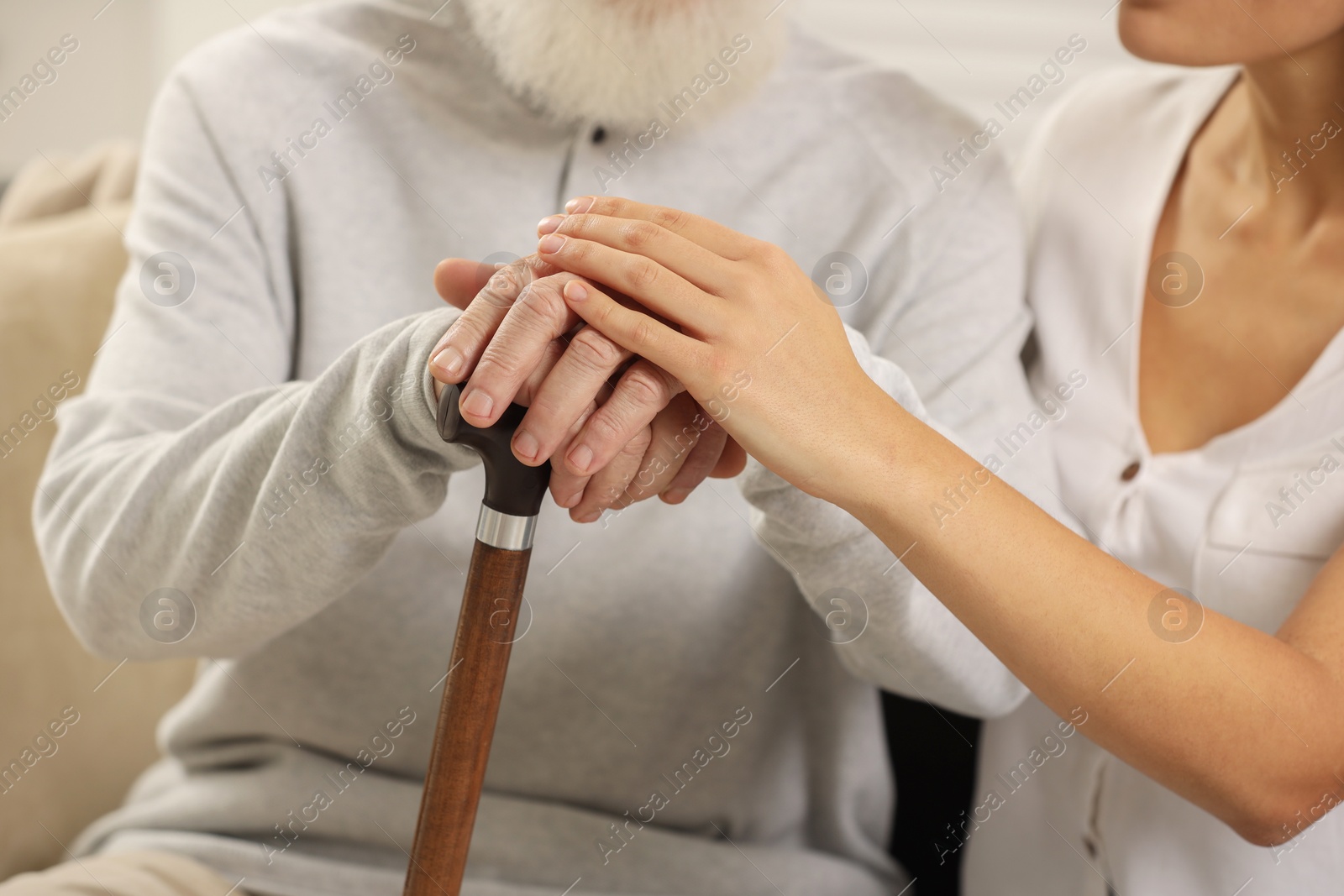 Photo of Senior man with walking cane and young woman indoors, closeup