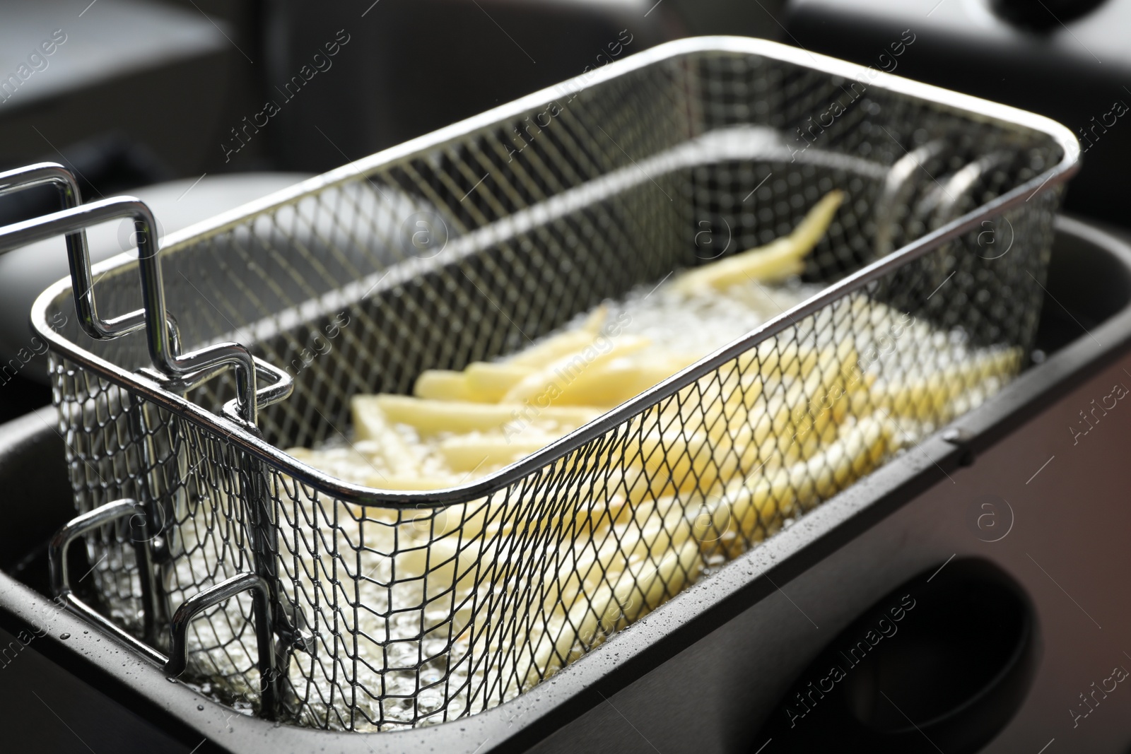 Photo of Cooking delicious french fries in hot oil, closeup