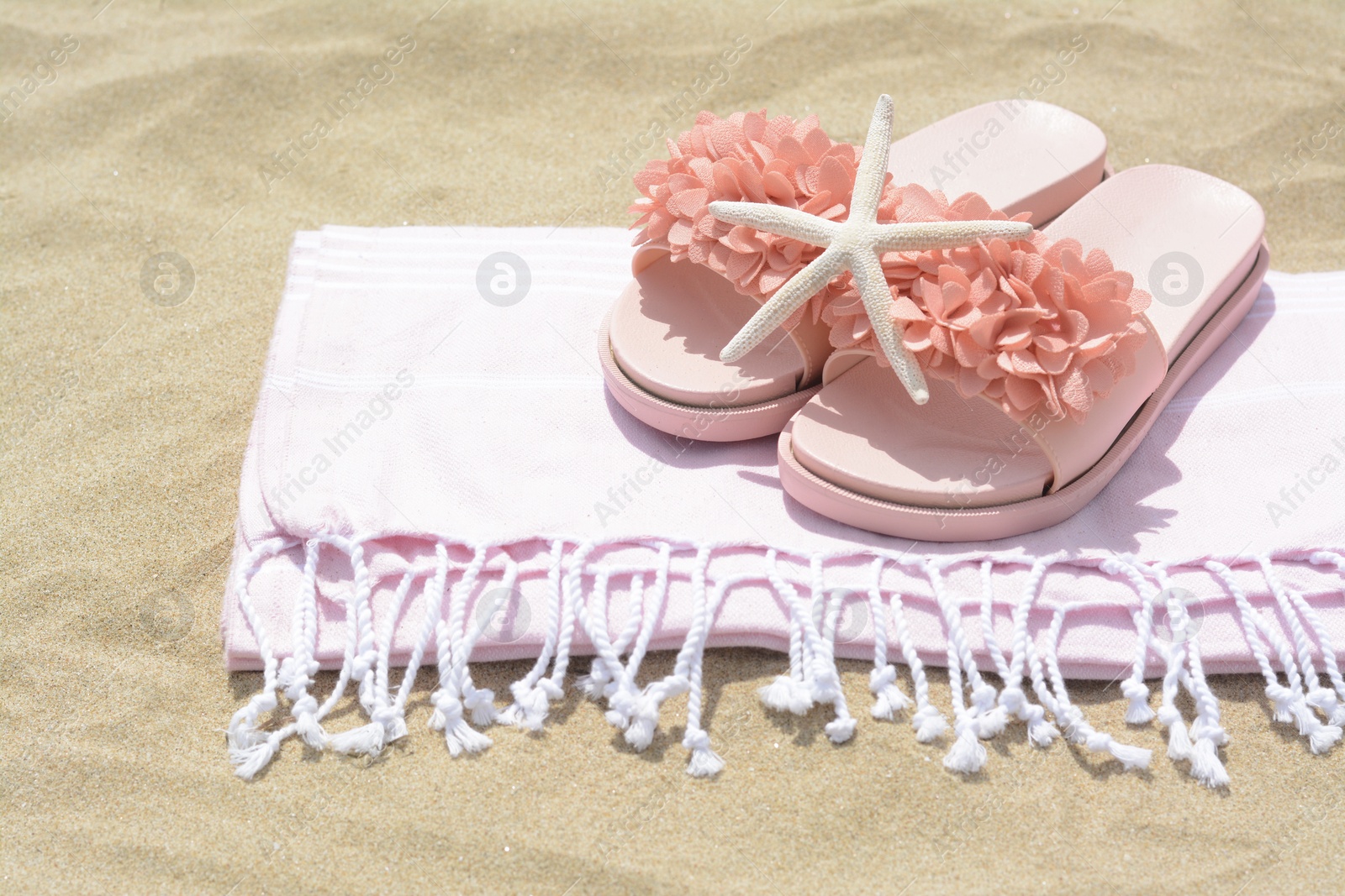 Photo of Blanket with stylish slippers and starfish on sand outdoors. Beach accessories