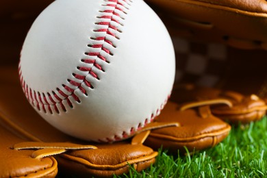 Photo of Catcher's mitt and baseball ball on green grass, closeup. Sports game