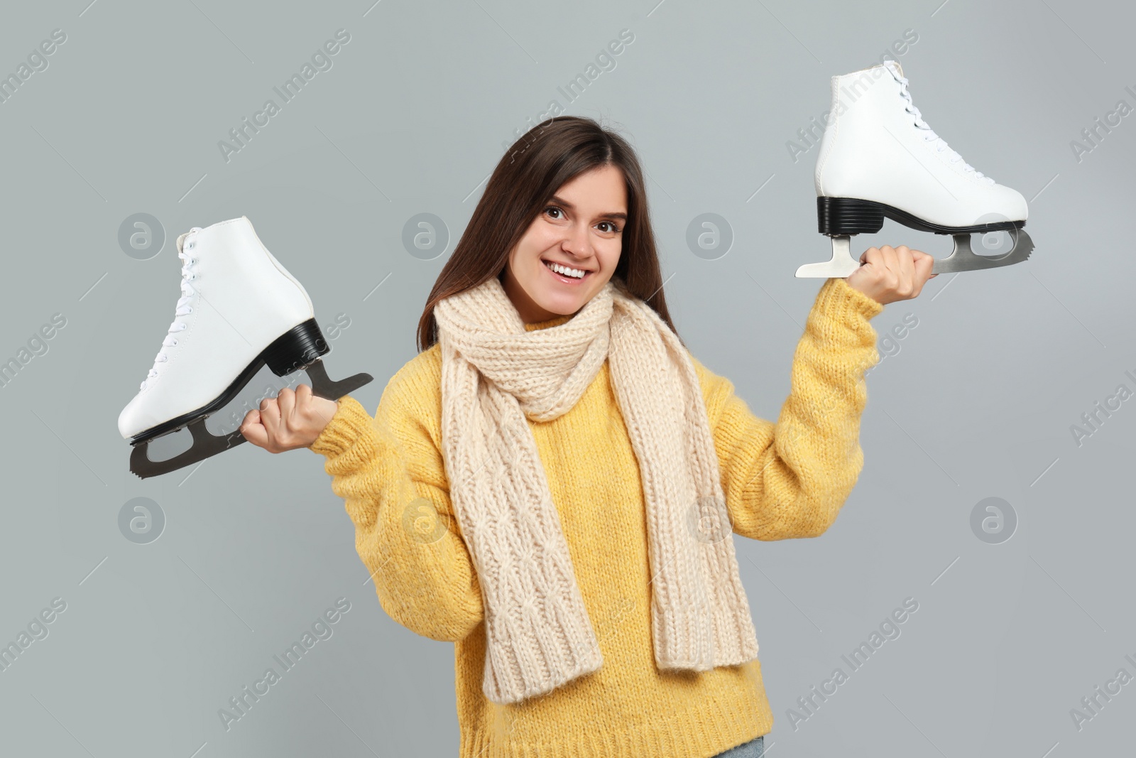 Photo of Happy woman with ice skates on grey background