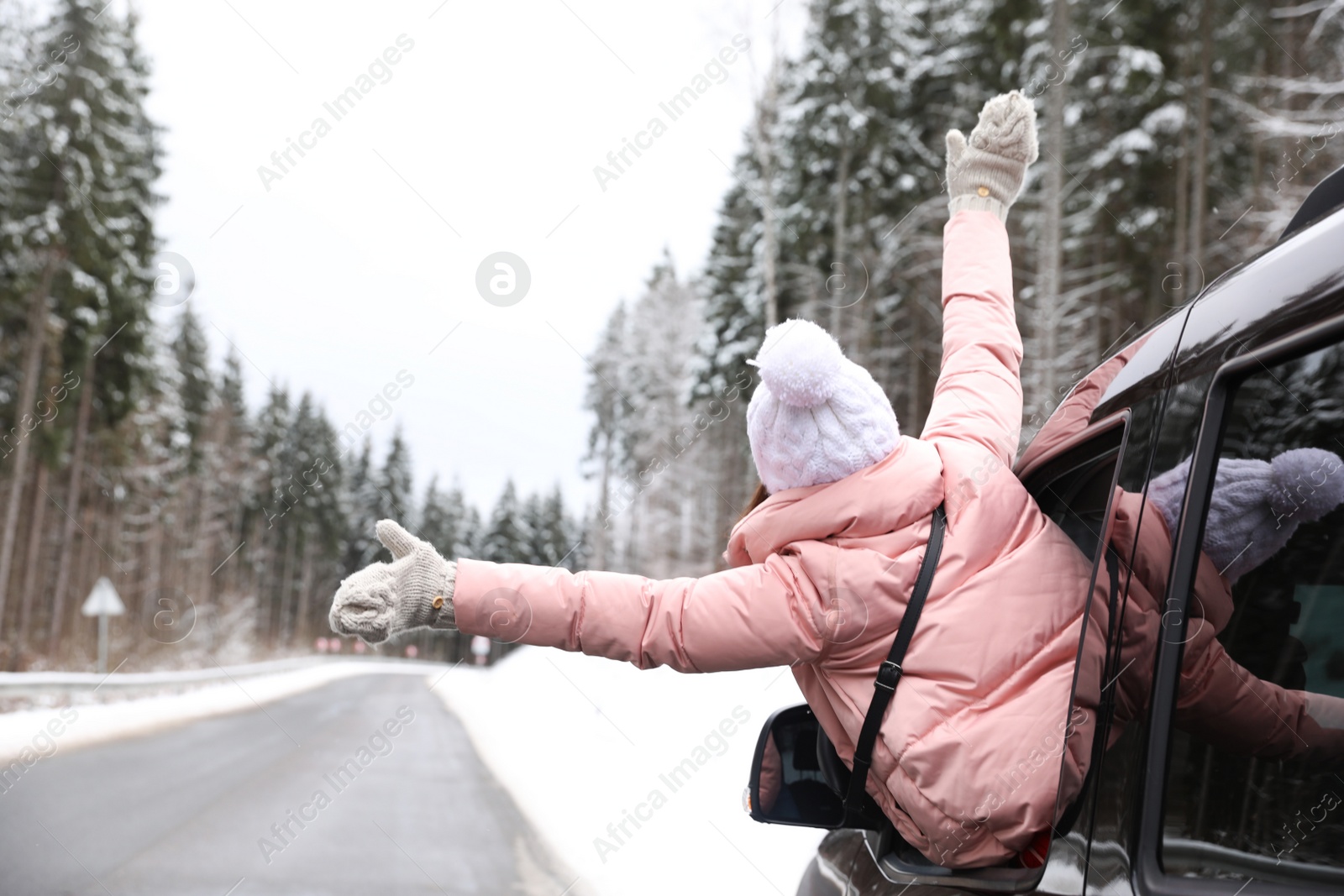 Photo of Young woman looking out of car window on road. Winter vacation