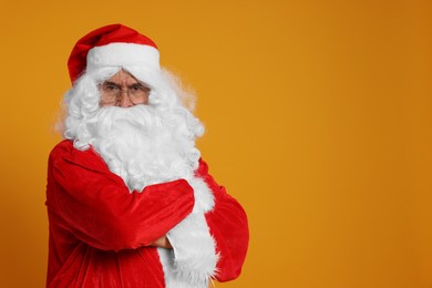 Photo of Merry Christmas. Angry Santa Claus on orange background, space for text