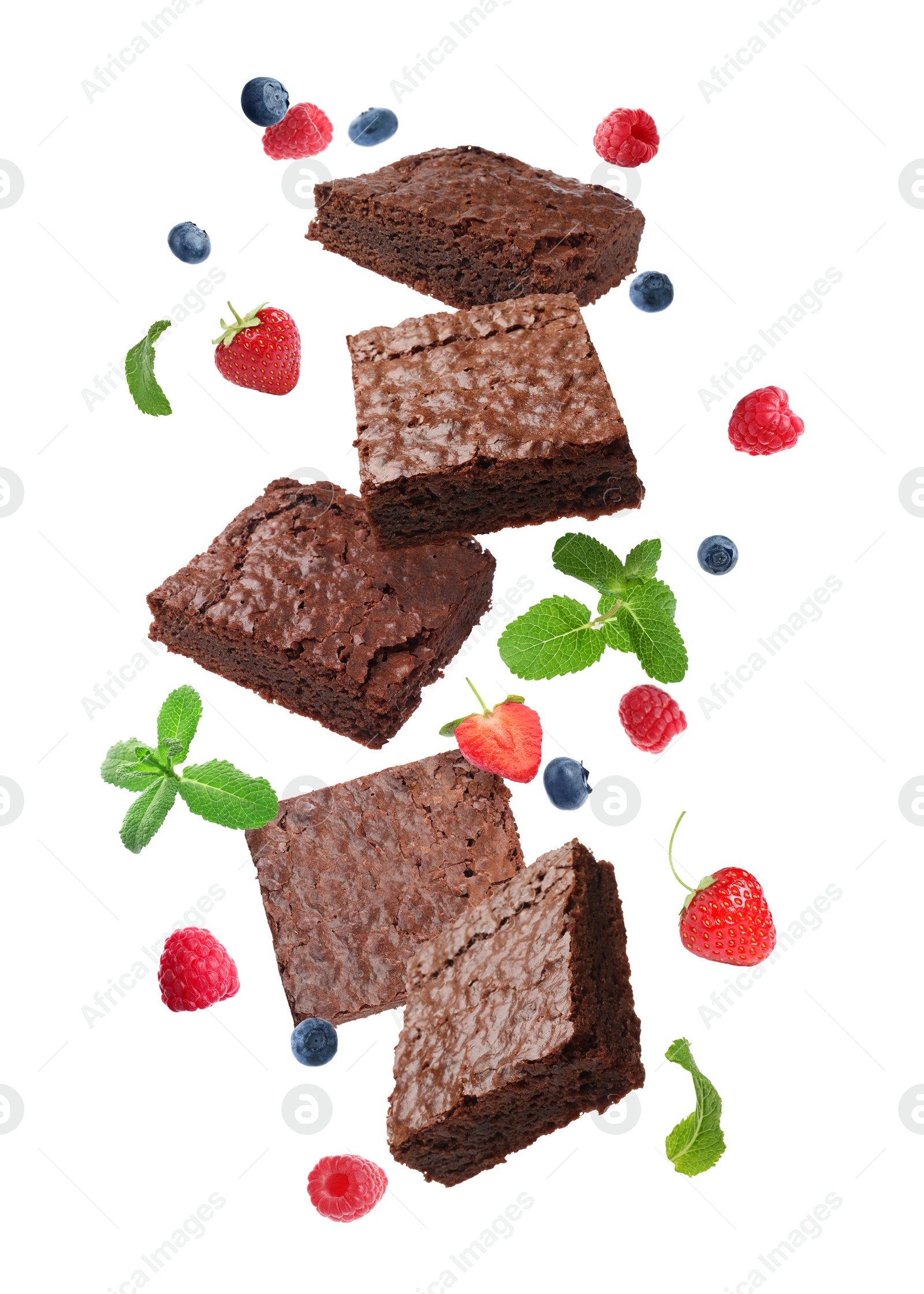 Image of Slices of delicious chocolate brownie with fresh berries and mint flying on white background