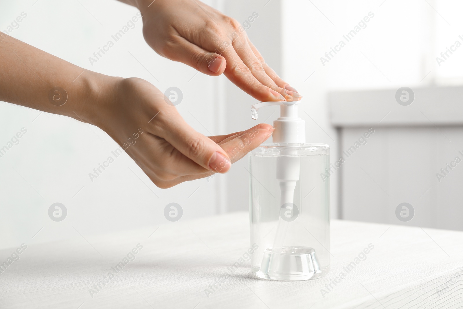 Photo of Woman applying antiseptic gel on hand indoors, closeup