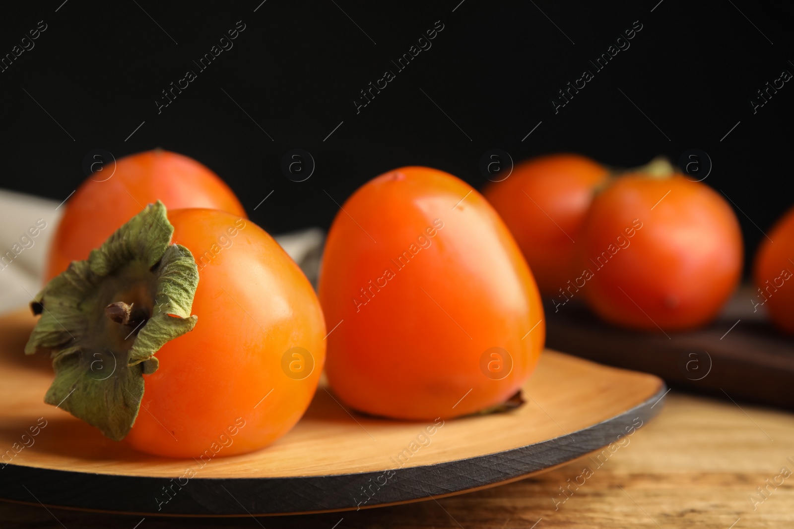 Photo of Tasty ripe persimmons on wooden table, closeup