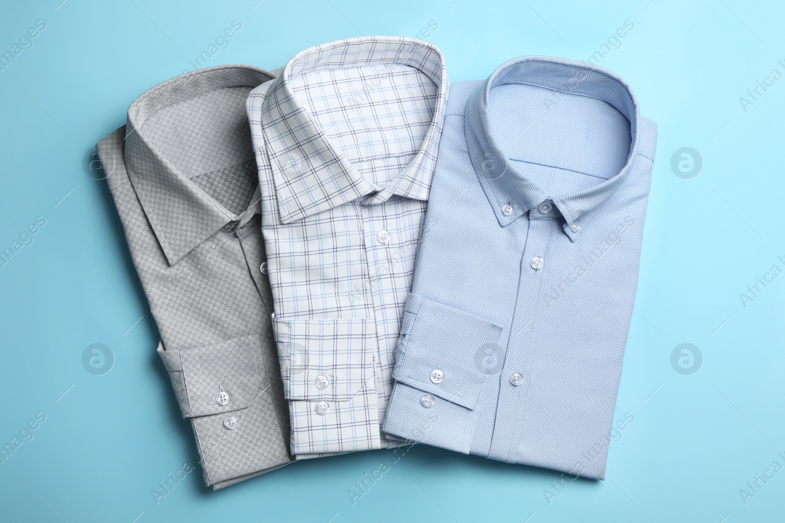 Photo of Stylish male shirts on light blue background, flat lay