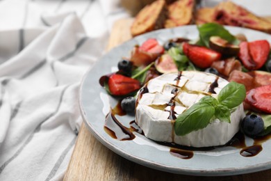 Delicious salad with brie cheese, berries and balsamic vinegar on board, closeup