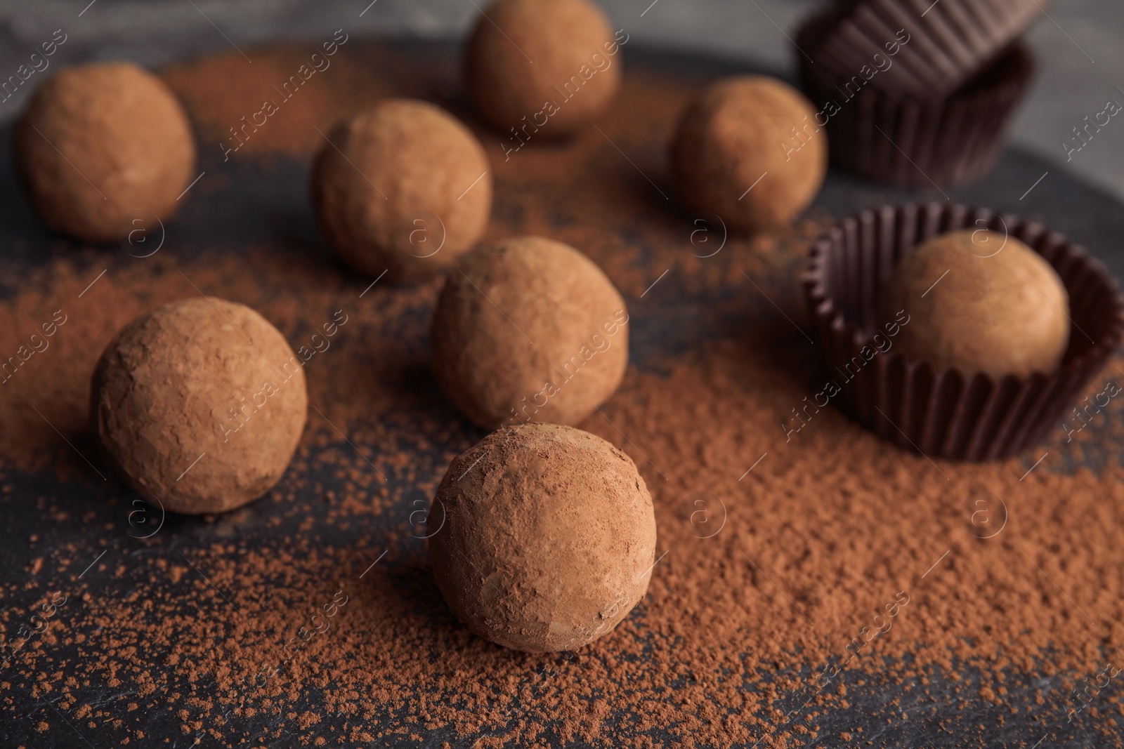 Photo of Chocolate truffles powdered with cocoa on slate plate, closeup