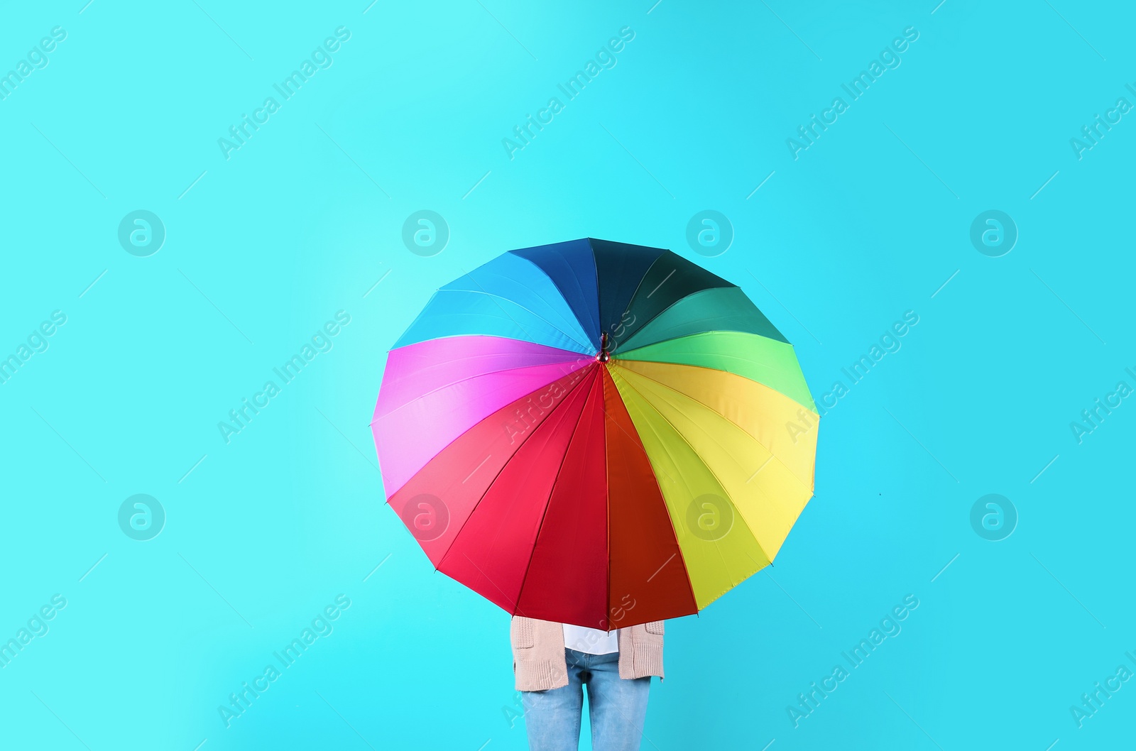 Photo of Woman hiding behind rainbow umbrella on color background